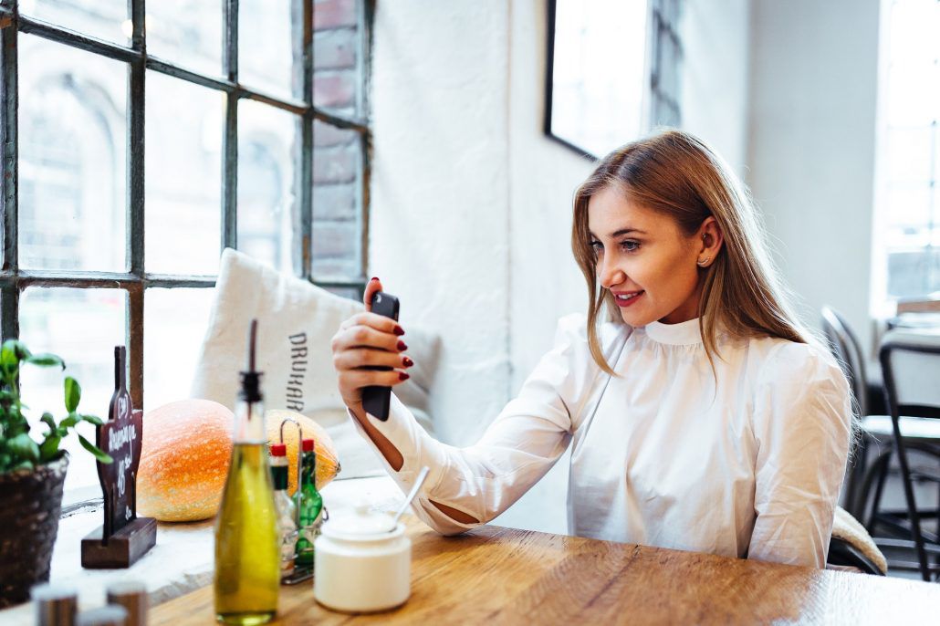 kaboompics Portrait of stylish young woman sitting at cafe and taking selfie with her smart phone